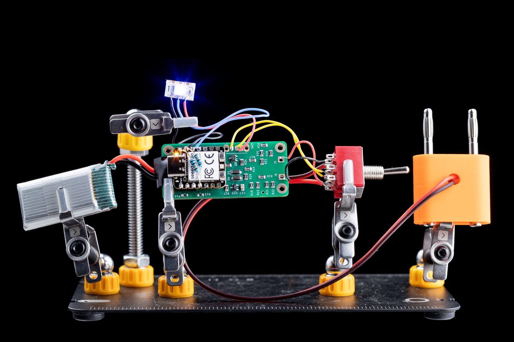 Exploded view of the DMM/minimalist build: PCB, MCU, toggle switch, banana plugs, LED and battery in helping-hands clamps.