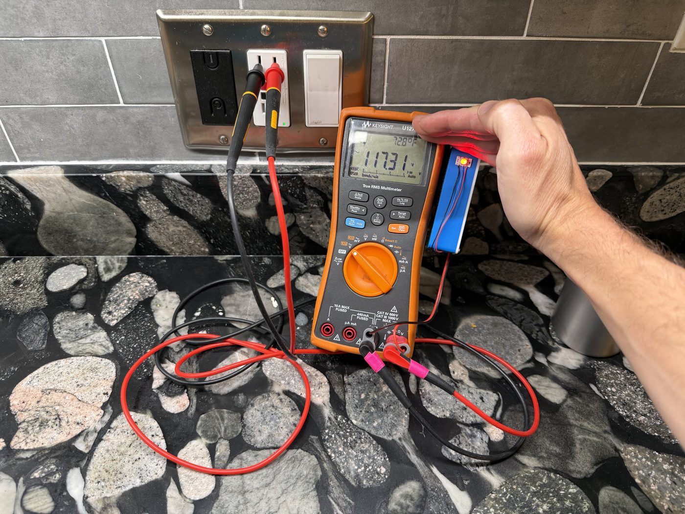 A meter with the red detector on a live 120 VAC outlet.